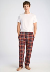 Röd och marinblå rutiga pyjamasbyxor med elastisk midja och dragsko, tillverkade av mjukt tyg, ihop med en enkel vit t-shirt.