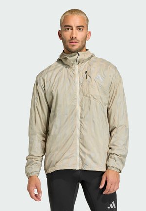 Lightweight beige jacket with a hood, featuring a subtle diagonal pattern, zippered chest pocket, and elastic cuffs. Designed for active use.