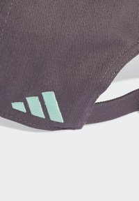 Podesiva bejzbol kapa od tamnopurpurog materijala s vertikalnim rebrastim uzorkom; sadrži akcentne logo detalje u mentol zelenoj boji izvezene koncem.