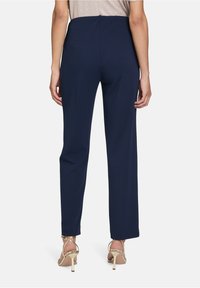 Navyblauwe, rechte broek met een hoge taille, gemaakt van een soepele stof. Kenmerkt zich door een schone achterkant en subtiele stikdetails.
