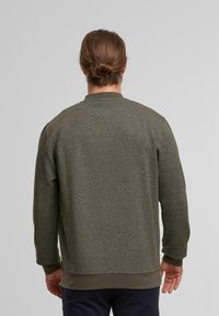 Mørkegrøn, struktureret sweatshirt med rund hals, ribbede mansjetter og kant. Har et diskret mønster og en afslappet pasform.