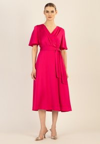 Fuchsia Wickelkleid mit kurzen Ärmeln, tailliertem Bund, knielangem Saum, glatter Textur und kombiniert mit transparenten Heels mit Verzierungen.