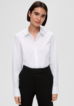 Chemise à manches longues avec col blanc, fabriquée en tissu lisse. Portée avec un pantalon noir ajusté ; présente un design classique.