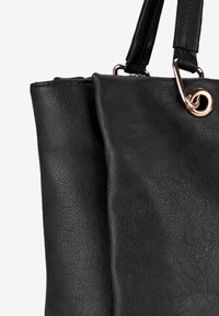 Borsa a tracolla in pelle nera con superficie testurizzata, dotata di doppi manici e un anello in metallo dorato. Visione ravvicinata del lato della borsa.