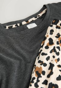 Mørkegrå bomulds T-shirt med leopardtryk i beige, sort og brune accenter. Rund halsudskæring med kontrasterende kant.