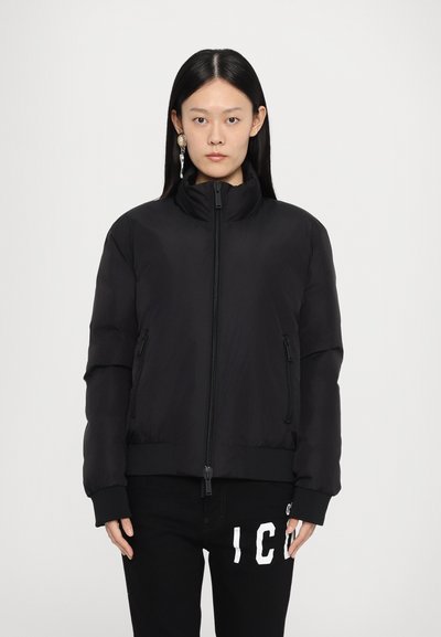 Veste bomber matelassée noire avec un col haut, deux poches zippées et des poignets côtelés. Texture lisse, design minimaliste et silhouette ajustée.