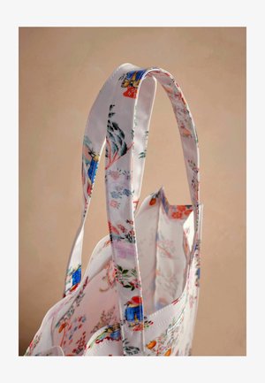 Gėlių raštuotas tote krepšys su baltu audiniu, pasižymintis spalvingais paukščių ir gėlių raštais, tvirtais rankenoms ir atvira viršūne.