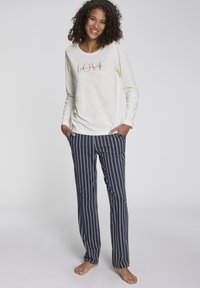 Long-sleeve cream top with "LOVE" graphic, paired with navy and gray striped pants. Soft fabric and relaxed fit, designed for comfort.