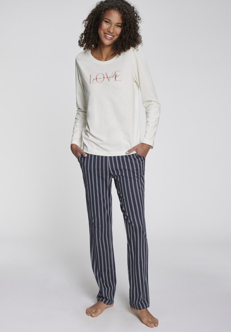 Long-sleeve cream top with "LOVE" graphic, paired with navy and gray striped pants. Soft fabric and relaxed fit, designed for comfort.