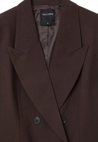 Brauner Blazer mit scharfen Revers, doppelreihigem Design und zwei schwarzen Knöpfen. Gefüttertes Innere mit sichtbarem Markenlabel "CALLIOPE".