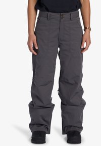 Grå snöbyxor med avslappnad passform, tillverkade av slitstarkt material. Har två framfickor, dragkedja vid underbenet och knäppning.