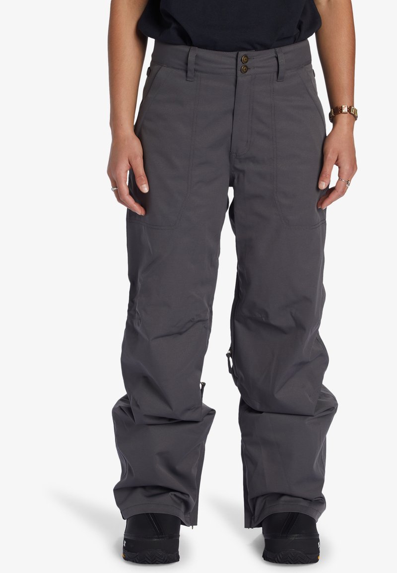 Grå snöbyxor med avslappnad passform, tillverkade av slitstarkt material. Har två framfickor, dragkedja vid underbenet och knäppning.