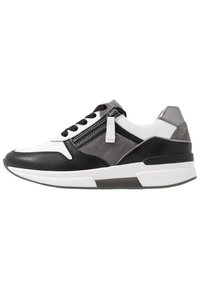 Svart och vit sneaker med ovandel i läder och mocka, snörningsdesign, sidoglidare och en tjock vit sula med en transparent del.