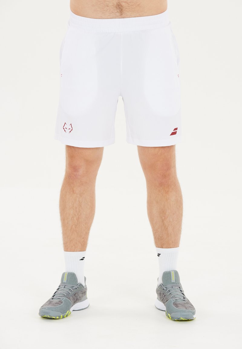 Mand iført hvide sportsshort med ulvlogo på venstre lår og grå atletiske sko med hvide sokker, stående på hvid baggrund.