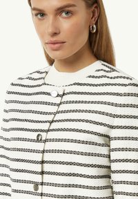 Witte en zwarte gestreepte cardigan met een gestructureerde afwerking, voorzien van een ronde halslijn en zilveren knoopaccenten.