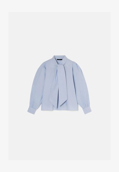 Ανοιχτό μπλε πουκάμισο με κορδόνι στο λαιμό, μακριά φουσκωτά μανίκια και κουμπωτές μανσέτες. Ο ιστός έχει λεία υφή με μια διακριτική γυαλάδα.