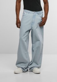 Jeans holgados de mezclilla en color azul claro, con diseño de pierna recta, detalles de costura sutiles y una cintura ancha.