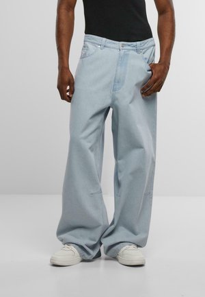 Šviesiai mėlynos laisvos džinsinės kelnės, pagamintos iš džinsinio audinio, su tiesiomis kojomis, subtiliomis siuvimo detalėmis ir plačiu juosmens diržu.