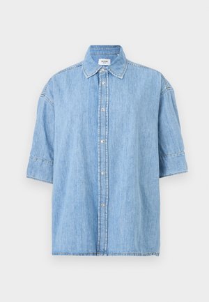 Gaiši zils džinsa īss piedurkņu krekls ar apkakli un redzamām priekšpuses pogām, attēlots uz gaiša vienveidīga fona.