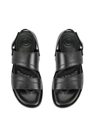 Schwarze Leder-Sandalen mit Kreuzriemen, offener Spitze, gepolstertem Fußbett und verstellbarem Schnallenriemen am Knöchel. Glatte Textur und quadratische Form.