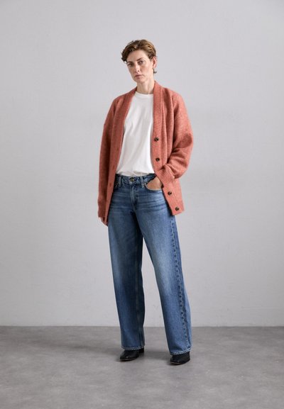 Coral knit cardigan with ribbed texture and black buttons, paired with light blue wide-leg jeans and black ankle boots.