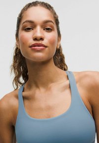 Débardeur de sport bleu clair avec un décolleté arrondi et des bretelles larges, confectionné dans un tissu lisse, présentant une coupe ajustée et une texture subtile.