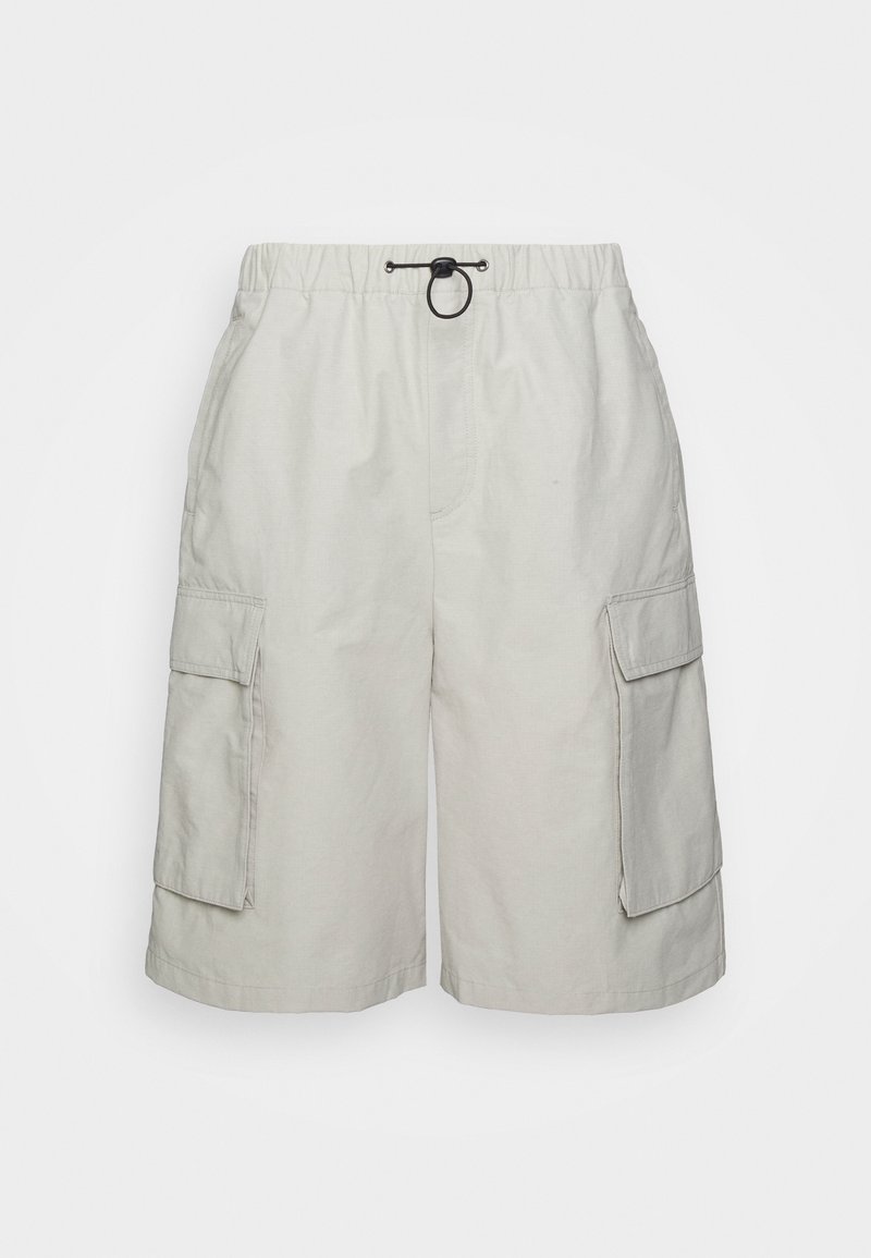 Short cargo beige clair avec taille élastique, cordon noir et grandes poches à rabat des deux côtés.