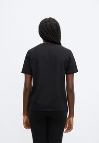 Fekete pamut rövid ujjú póló, kerek nyakkivágással és szabványos szabással. Egyszerű hátoldal, grafikák vagy díszítések nélkül.