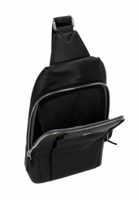 Bolsa de cuero negro tipo bandolera con una textura suave, compartimento principal con cremallera y bolsillo forrado en gris. Incluye una correa ajustable y herrajes plateados.