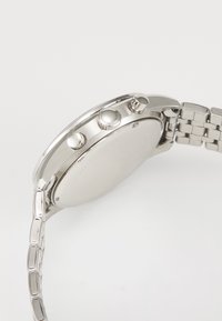 Ασημένιο μεταλλικό ρολόι χειρός με τρία πλευρικά κουμπιά και αλυσίδα βραχιολιού σε λευκό φόντο.