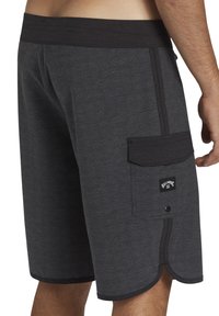 Shorts de bain Billabong en gris foncé avec un motif circulaire subtil, taille élastique et poche latérale avec détail du logo.