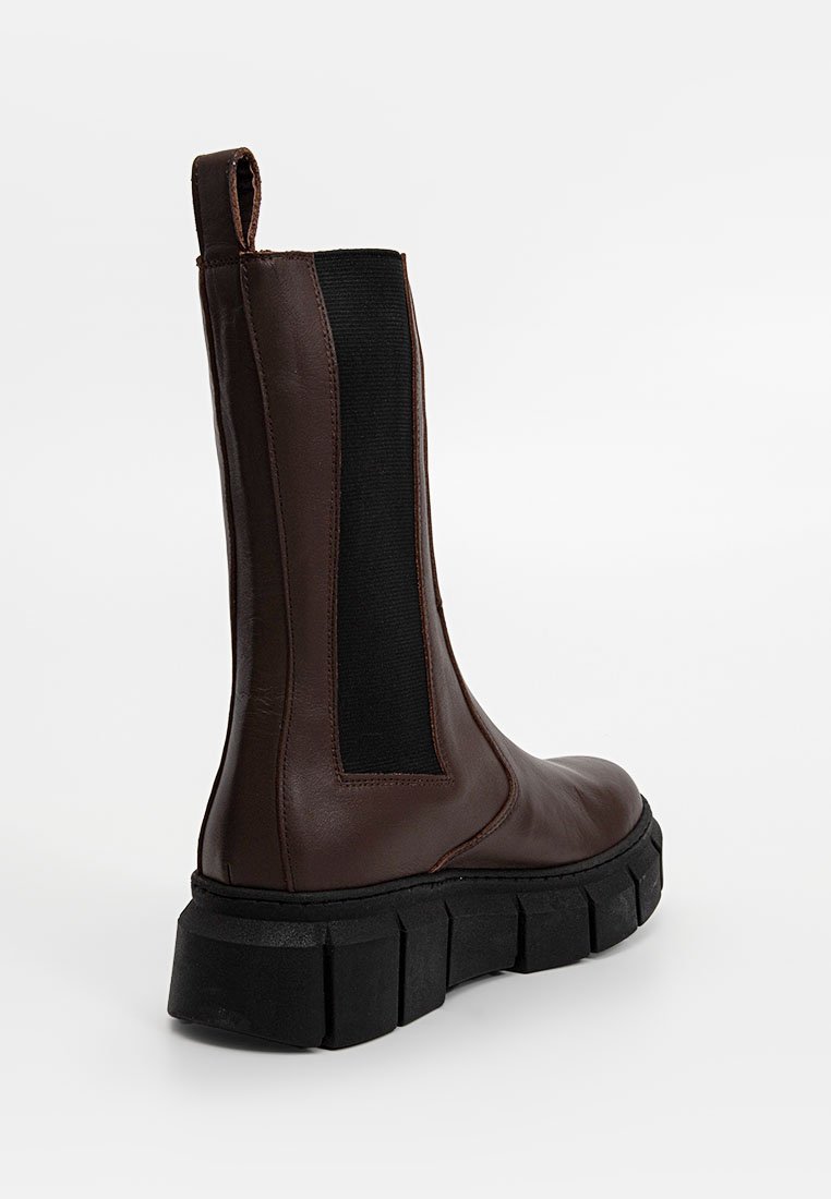 Bottine en cuir marron foncé avec panneau latéral élastique noir et semelle épaisse noire, vue de l'arrière sur fond blanc.