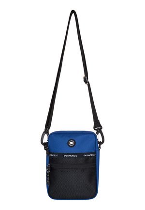 Bolso cruzado de tela azul con bolsillo frontal de malla negra, parche con logo y correa ajustable. Cuenta con un cierre de cremallera y materiales duraderos.