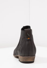 Schwarze Leder-Stiefelette mit Holzabsatz, vertikalen Nähten, elastischem Seitenpaneel und einer Zuglasche mit einem Vogelemblem und orange farbigen Nähten.