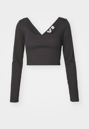 Svart ribbet langermet crop top med dyp V-hals og tettsittende design. Har merker på innsiden av halsen. Glatt tekstur.