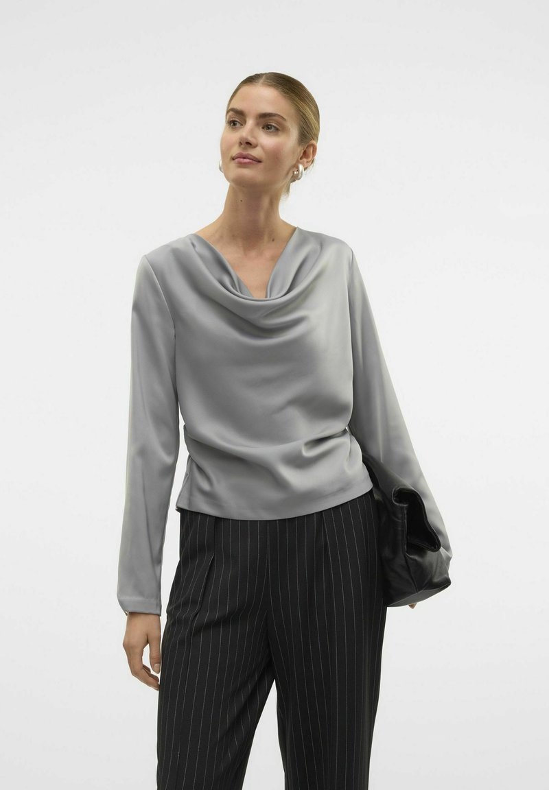 Maglione grigio con collo a cowl e maniche lunghe, realizzato in tessuto morbido, abbinato a pantaloni neri con righe sottili, caratterizzati da un design elegante e una vestibilità raffinata.