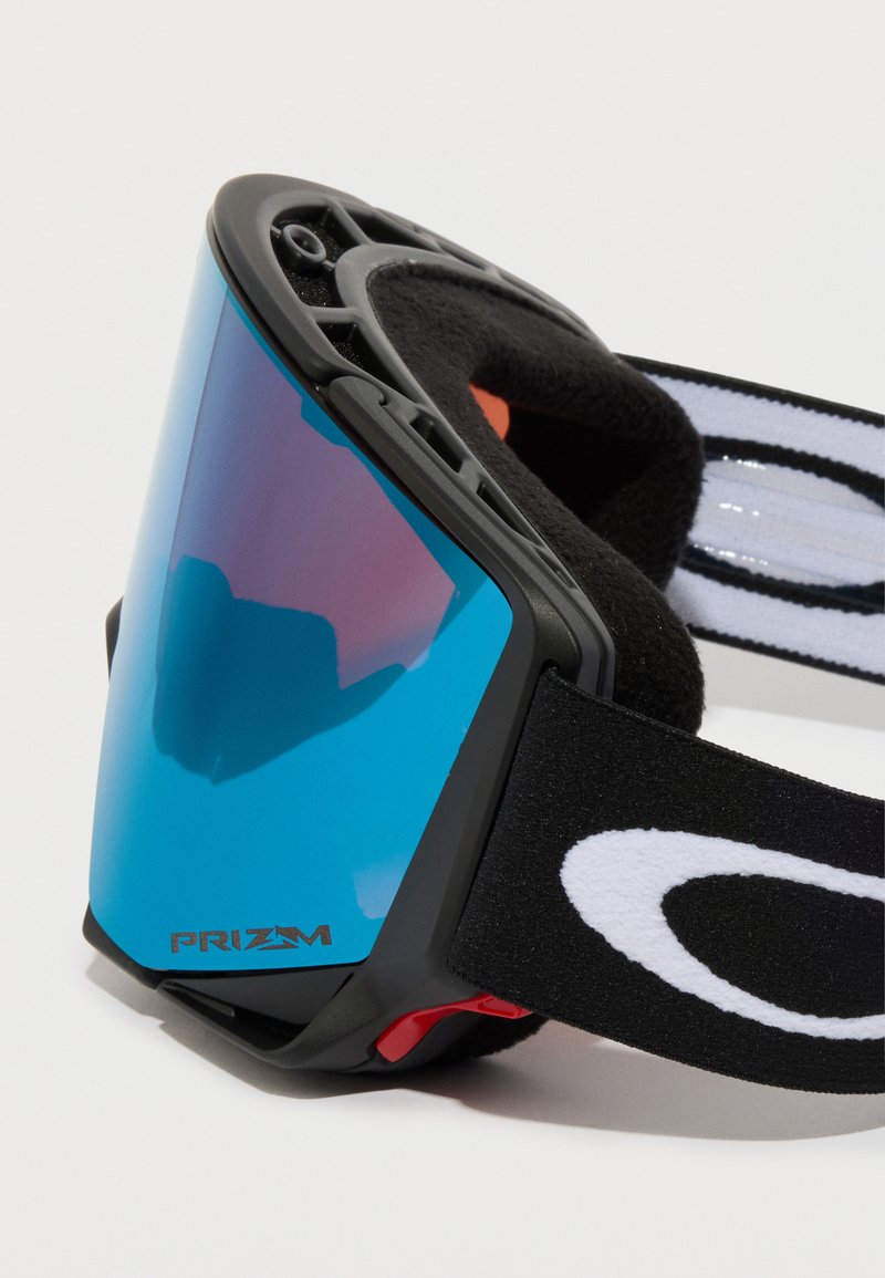 Skibriller med en stor, buet blå linse, sort gummiramme og justerbar sort rem med en hvid logo-accent.