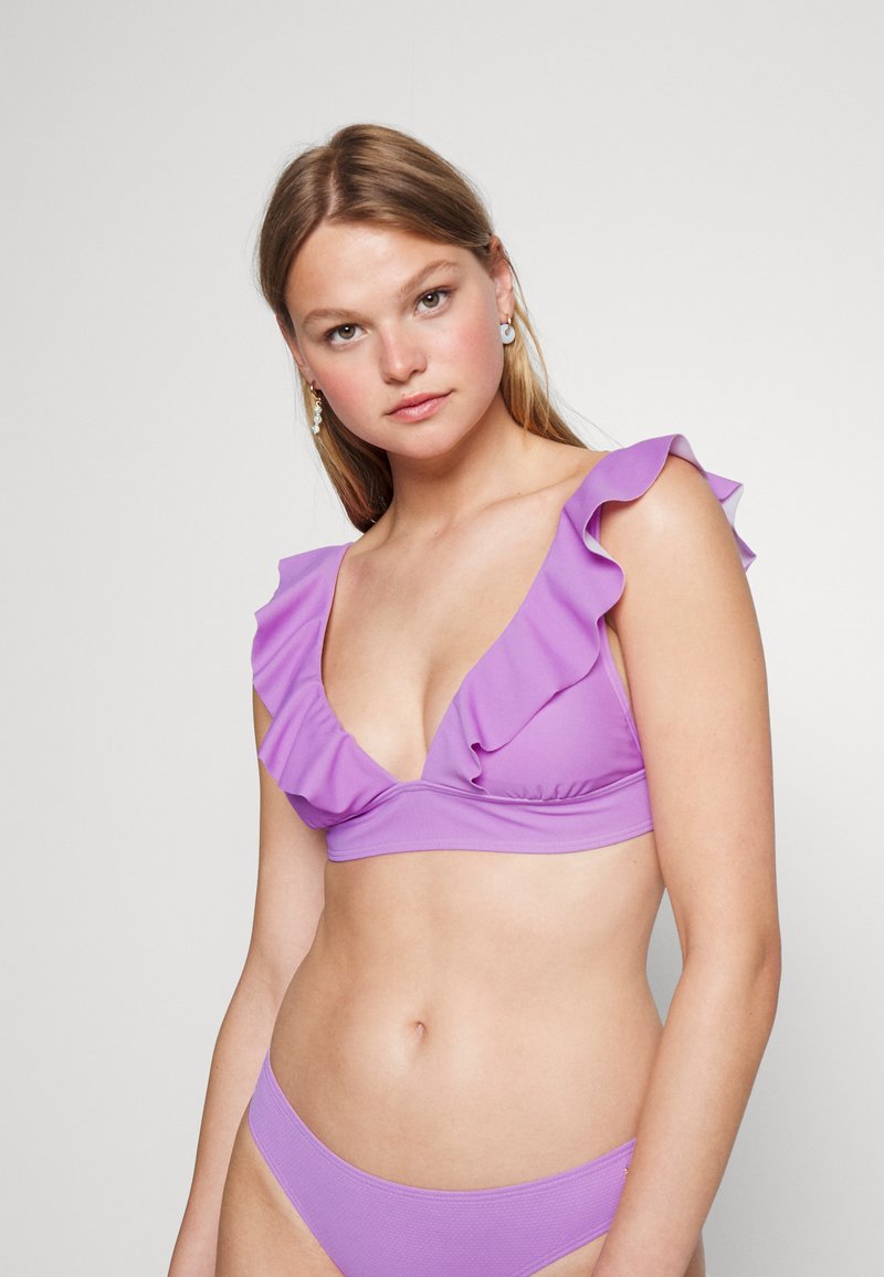 Conjunto de bikini roxo feito de tecido suave. O top apresenta detalhes com babados e um decote em V profundo; as partes de baixo têm um design simples e coordenado.