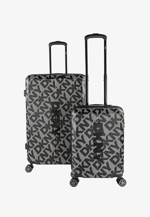 Dos maletas DKNY en negro y gris con un patrón audaz de logotipos. La maleta más grande tiene una forma rectangular con texturas suaves y cuatro ruedas.