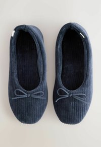 Siniste korgiga sussid pehme tekstuuriga, ümarate varvaste ja esiosas dekoratiivse lipsuga. Sisevooder on tumeda värviga.