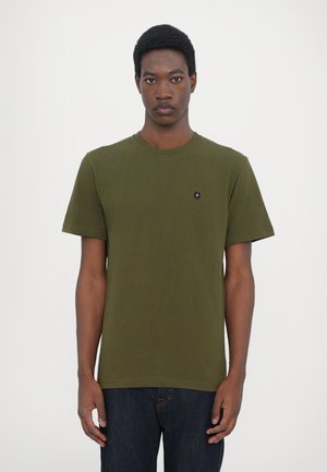 Olive green cotton t-shirt with short sleeves, round neckline, and small black emblem on the chest. Worn with dark denim jeans.
