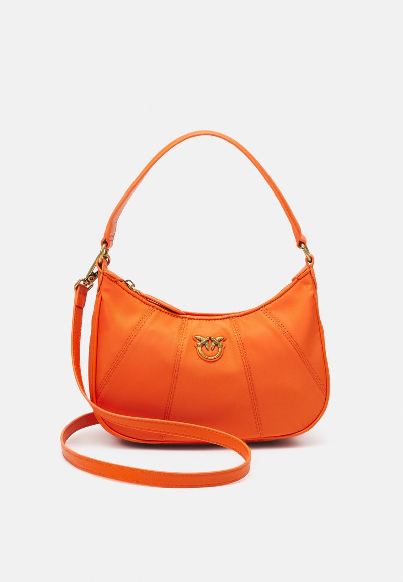 Petit sac bandoulière orange avec bretelles courtes et longues, emblème logo doré et détails de panneaux cousus sur matière lisse.