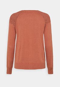 Svetr v rezavě hnědé barvě s kulatým výstřihem, dlouhými rukávy a složitým pleteným detailem na ramenou. Měkká textura a žebrovaný lem.