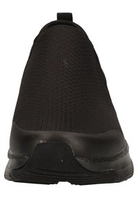 Zapatilla negra sin cordones con un upper de malla texturizada, puntera redondeada y una suela de goma flexible con detalles de relieve sutiles.
