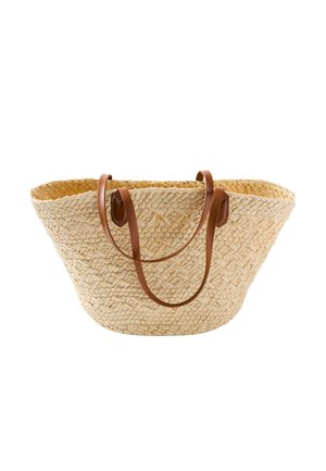 Sac cabas en paille tressée avec deux bretelles en cuir marron, large ouverture en haut et fond légèrement effilé sur fond blanc.