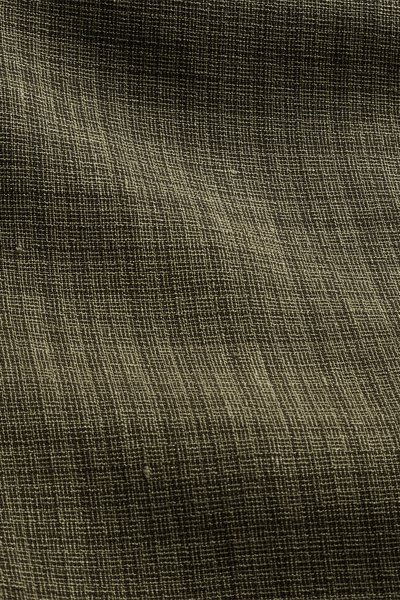 Gros plan d'un tissu vert olive foncé avec une texture tissée grossière et des fils irréguliers visibles.
