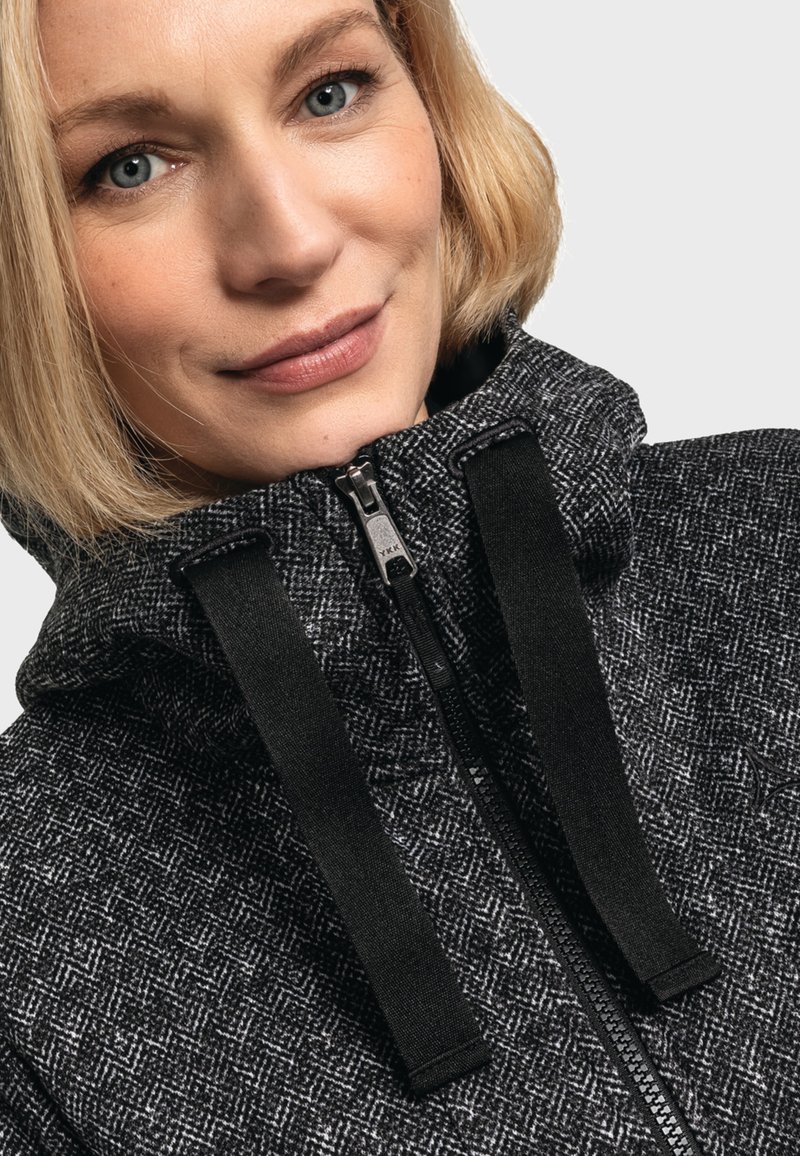 Felpa con cappuccio grigio scuro realizzata in un morbido tessuto dalla texture con motivo a spina di pesce, dotata di una cerniera frontale e spalline nere regolabili.