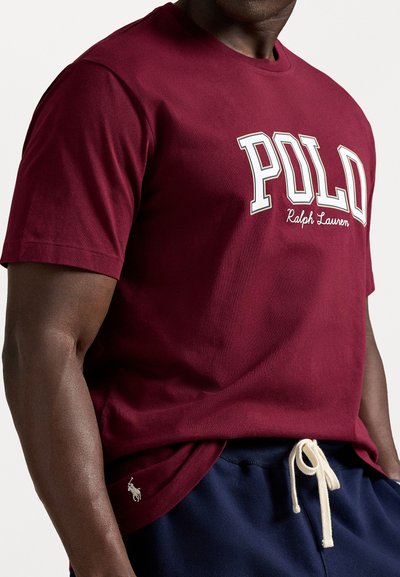 Burgundy pamut póló "POLO Ralph Lauren" felirattal fehér színben. Rövid ujjú, kerek nyakú, kis logóval a szegélyen.