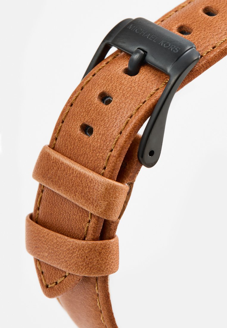 Leren horlogeband in lichtbruin met een gestructureerd oppervlak, voorzien van een zwarte metalen gesp en lusaccenten voor een veilige aanpassing.