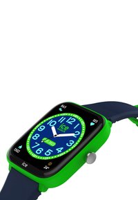 Orologio smartwatch in silicone verde con quadrante quadrato, quadrante blu, grandi numeri bianchi, display della data e pulsante laterale argentato su un cinturino blu navy.